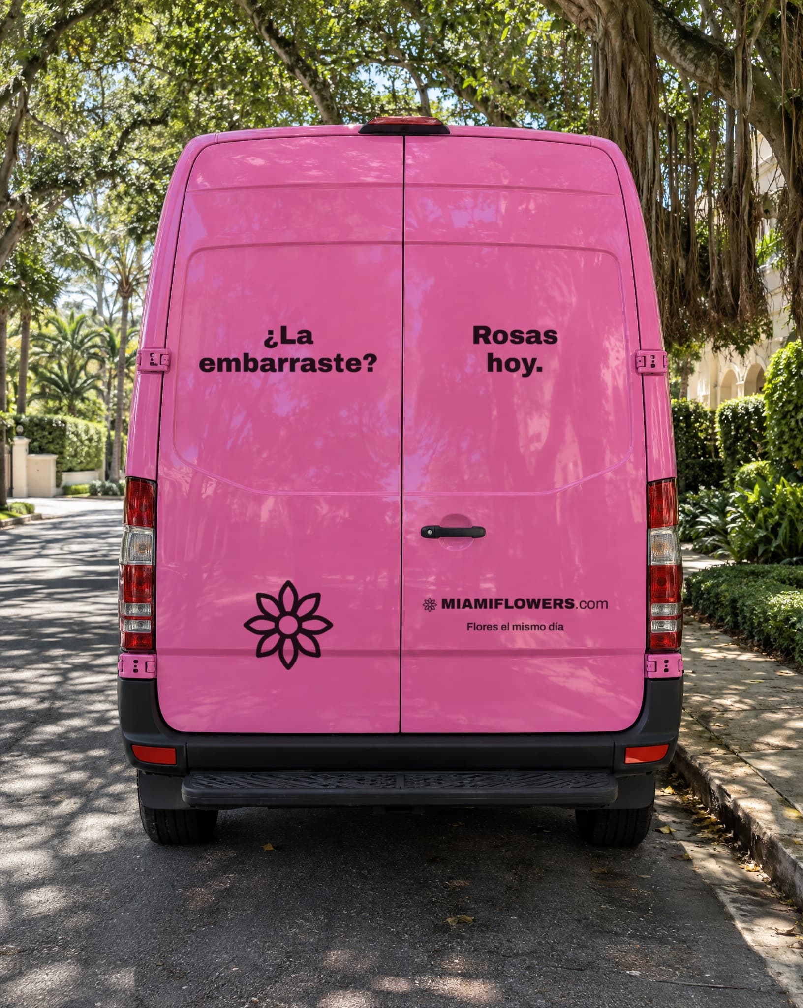 Puertas traseras de una camioneta rosada de MIAMIFLOWERS.com que dicen '¿La embarraste? Rosas hoy. Flores el mismo día.'