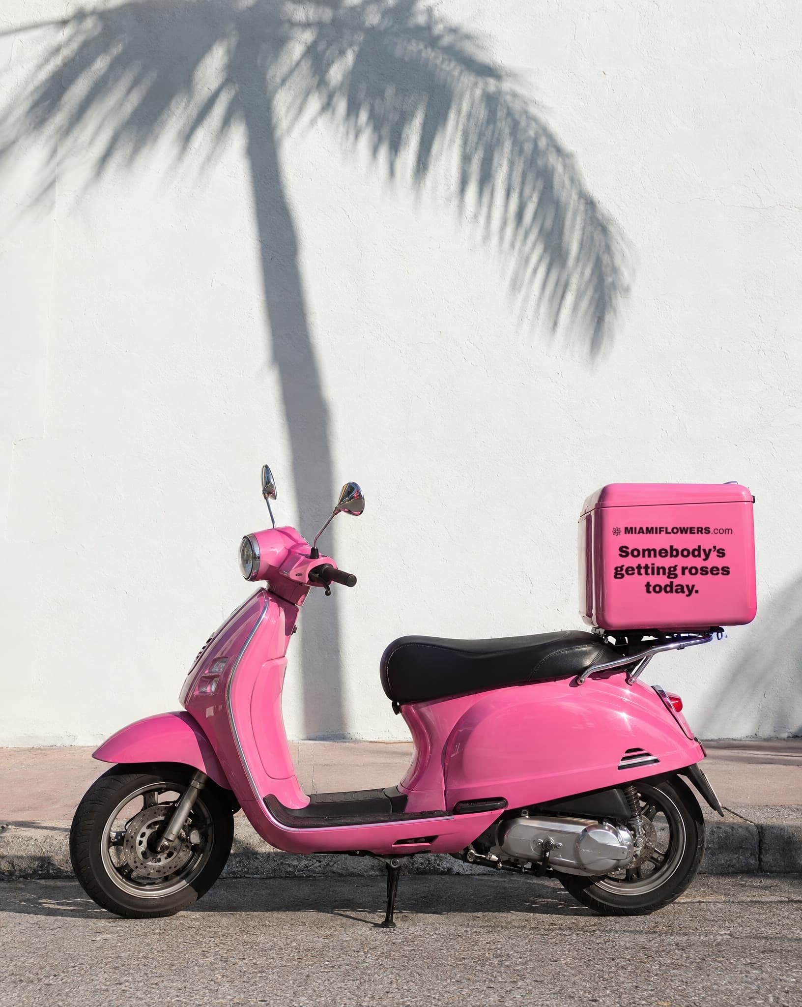 A pink Miami Flowers scooter by a white wall, its box reading: Somebody's getting roses today