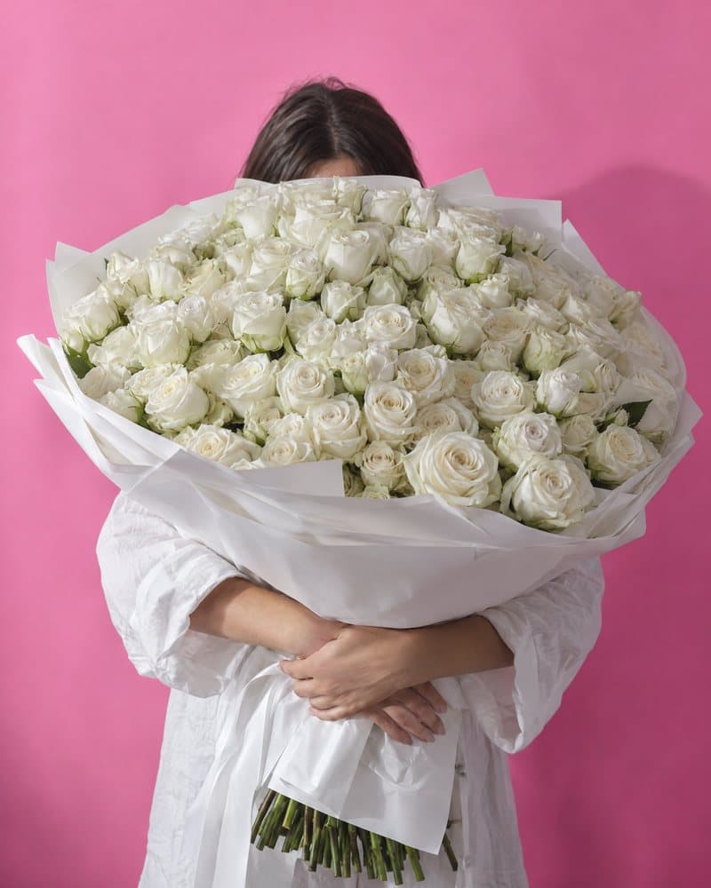 Woman hugging a large bouquet of white roses